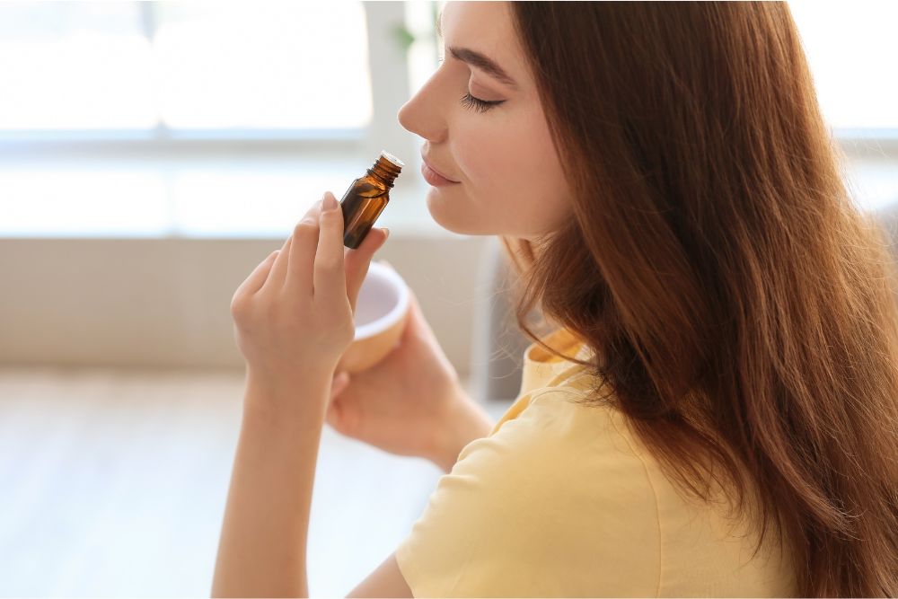 Mujer relajándose con aceites esenciales y difusor en un ambiente acogedor