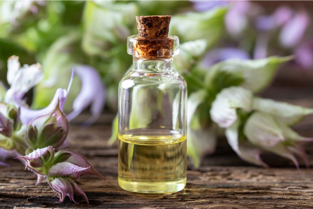 Aceite esencial de salvia en un frasco con hojas frescas de salvia