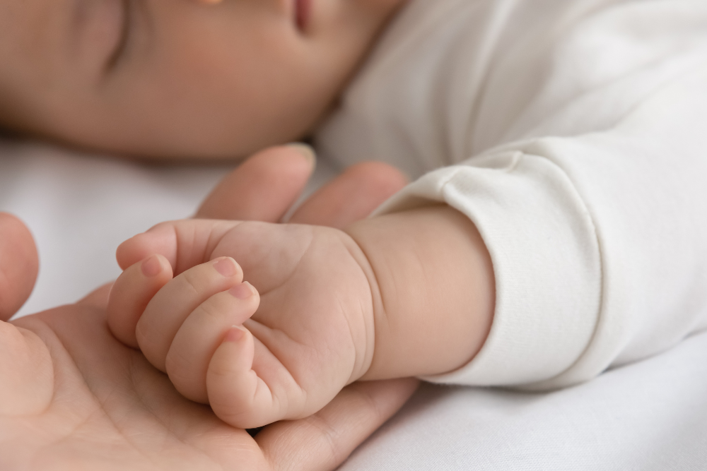 Detalle de la manita de un bebé en la palma de un adulto, símbolo de sensibilidad y de la necesidad de protección