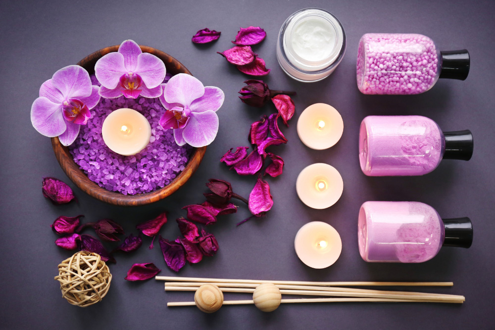 Composición aromaterapéutica con orquídeas moradas, velas encendidas, sal y aceites esenciales