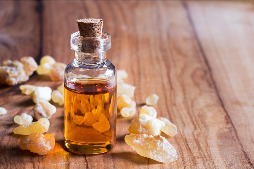 Aceite esencial de incienso en un frasco con bolitas de incienso sobre una base de madera