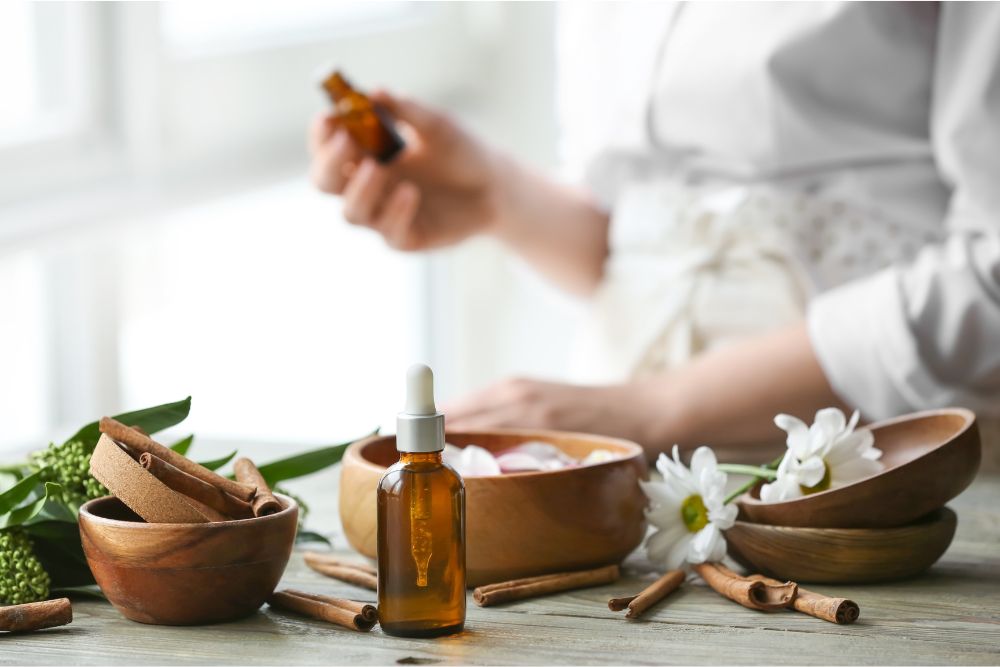 Botellas de vidrio con aceites esenciales rodeadas de hierbas frescas y flores