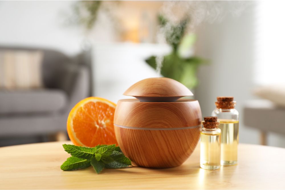 Difusor de aromas de madera con aceites esenciales, menta y naranja en un acogedor interior doméstico.