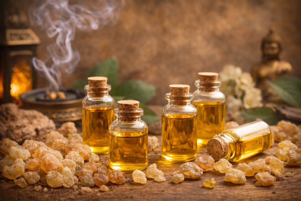 Aceites esenciales de incienso en pequeños frascos de vidrio rodeados de trozos de resina de incienso sobre una base natural de madera
