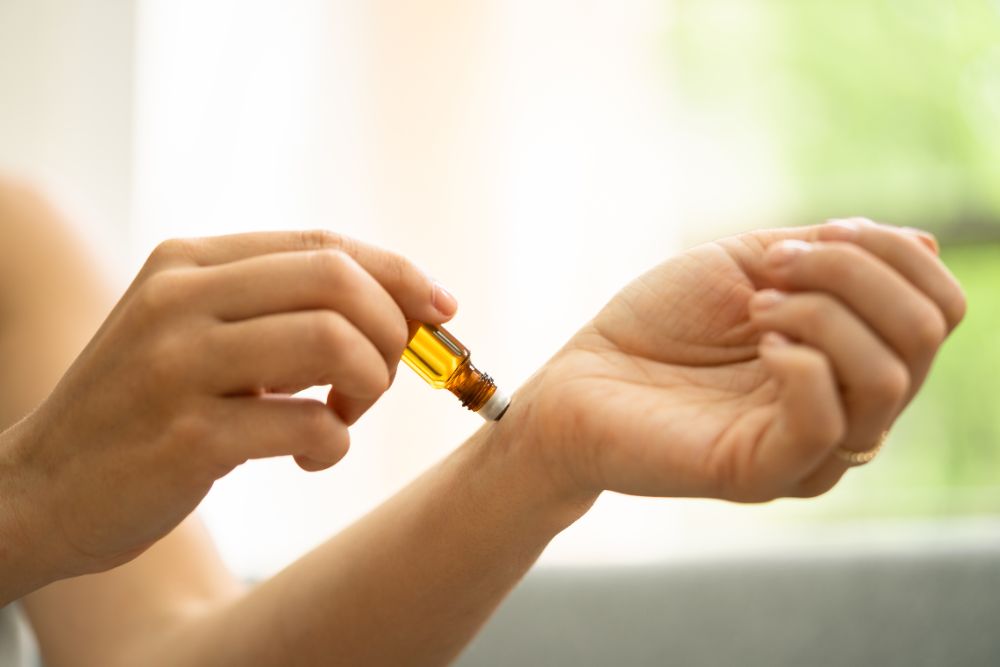 Aplicación de aceite esencial en la muñeca: muestra de un uso seguro de la aromaterapia en el entorno doméstico.
