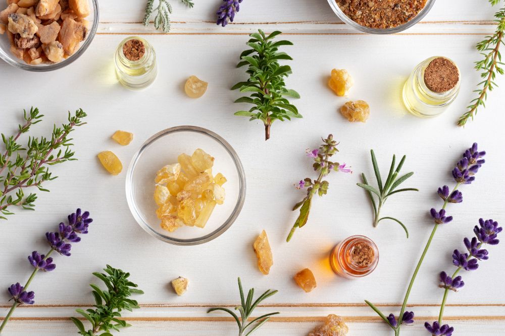 Frascos con aceites esenciales rodeados de hierbas frescas y flores para aromaterapia