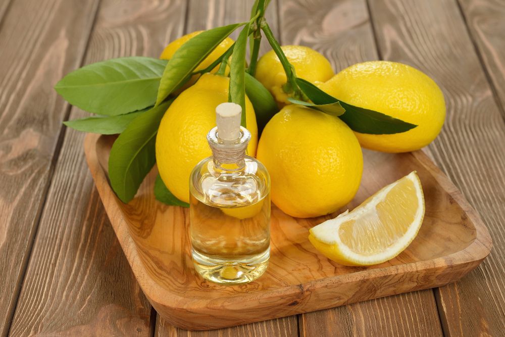 Aceite de limón en un frasco pequeño con limones frescos sobre una base de madera