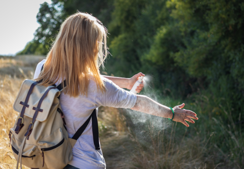 Mujer al aire libre usando un spray natural contra mosquitos