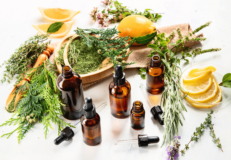 Aceites esenciales en frascos marrones rodeados de hierbas y limones.