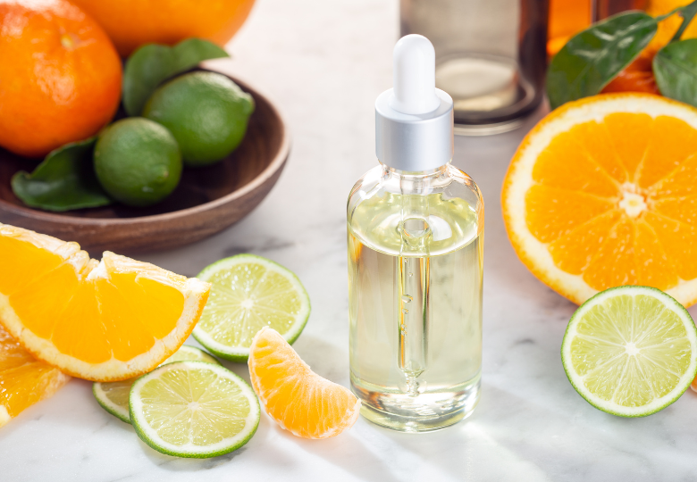 Frasco de aceite esencial de limón entre rodajas frescas de cítricos: un producto natural para limpiar sin química.